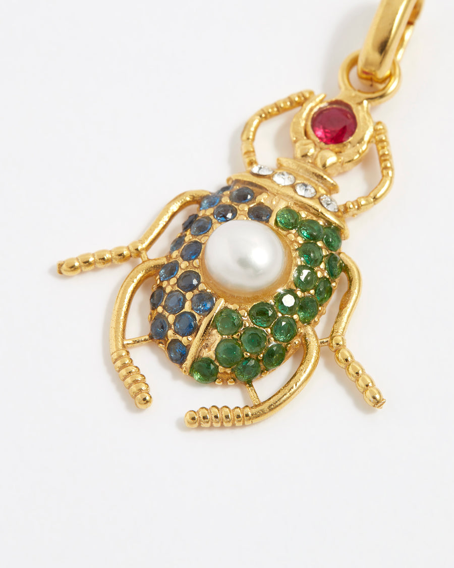 product shot of scarab beetle charm encrusted with red, bue and green crystals and one pearl on the back close up