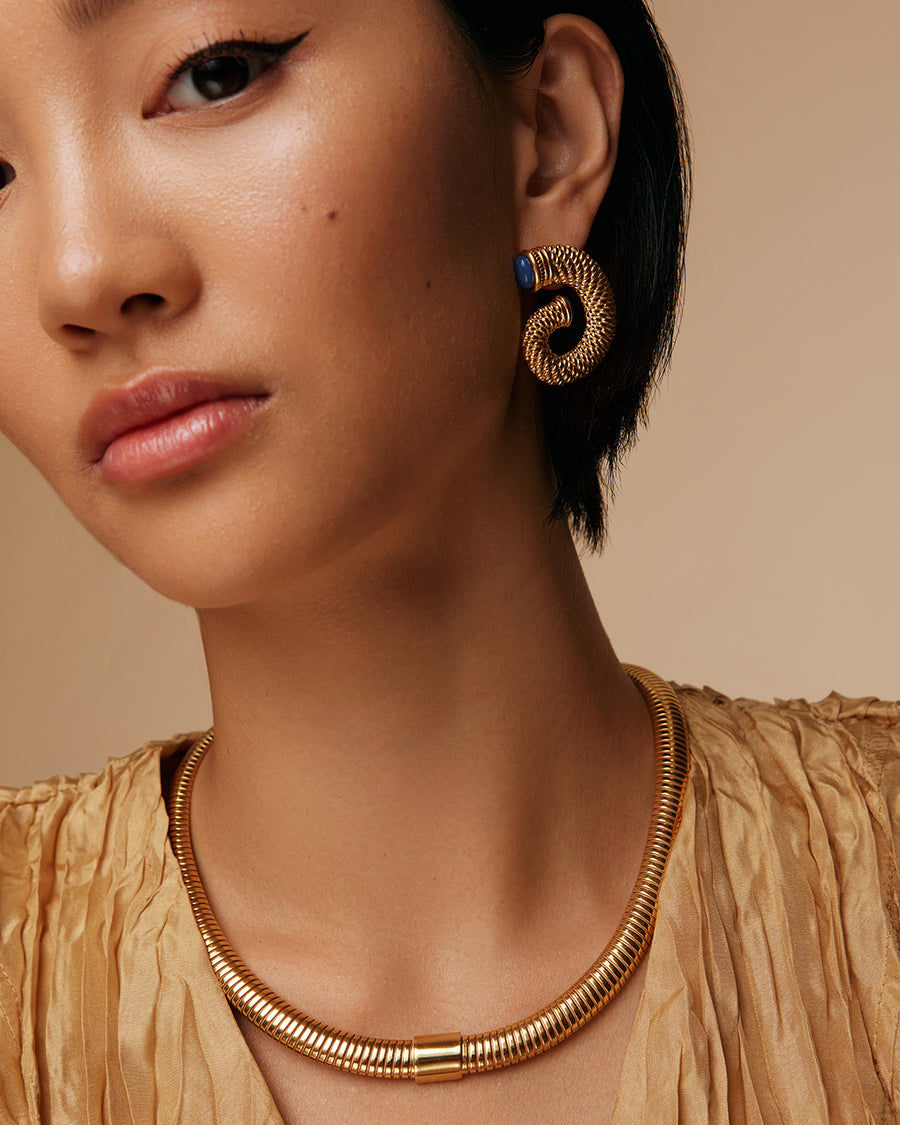 on model shot of yellow gold plated oversized stud earring with twisted gold and blue ends