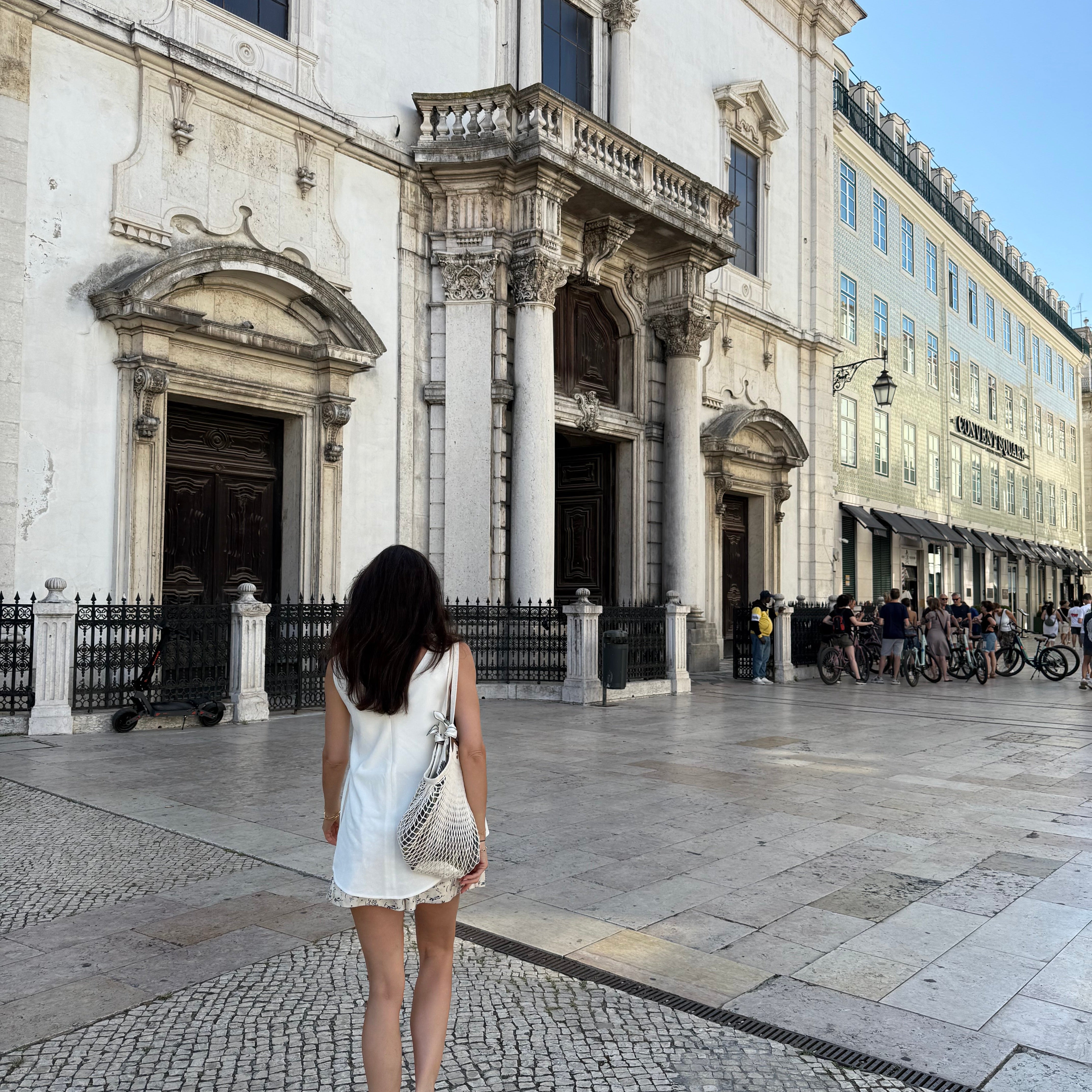 back of marianna walking in Lisbon, portugal towards a church