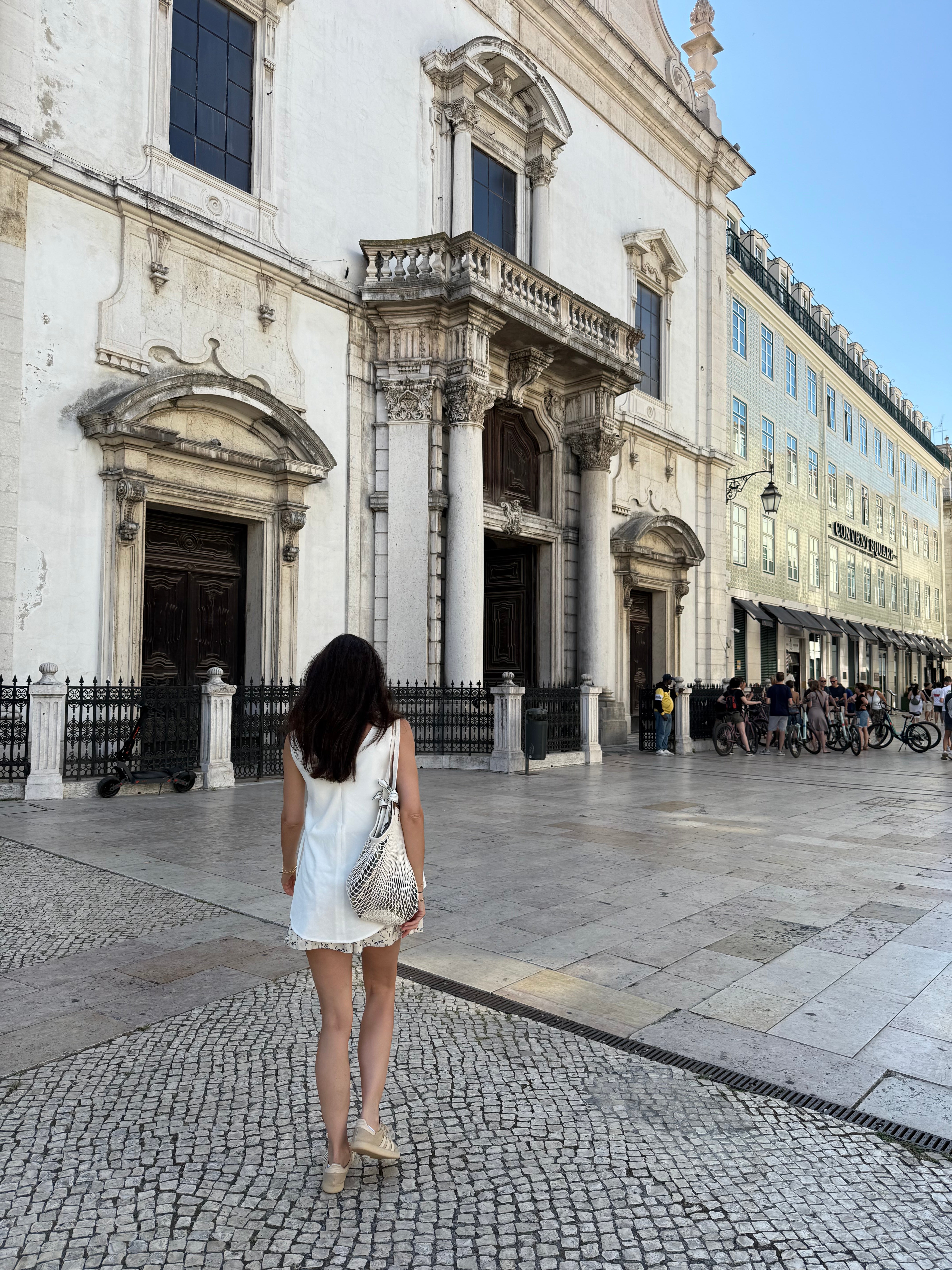 back of marianna walking in Lisbon, portugal towards a church