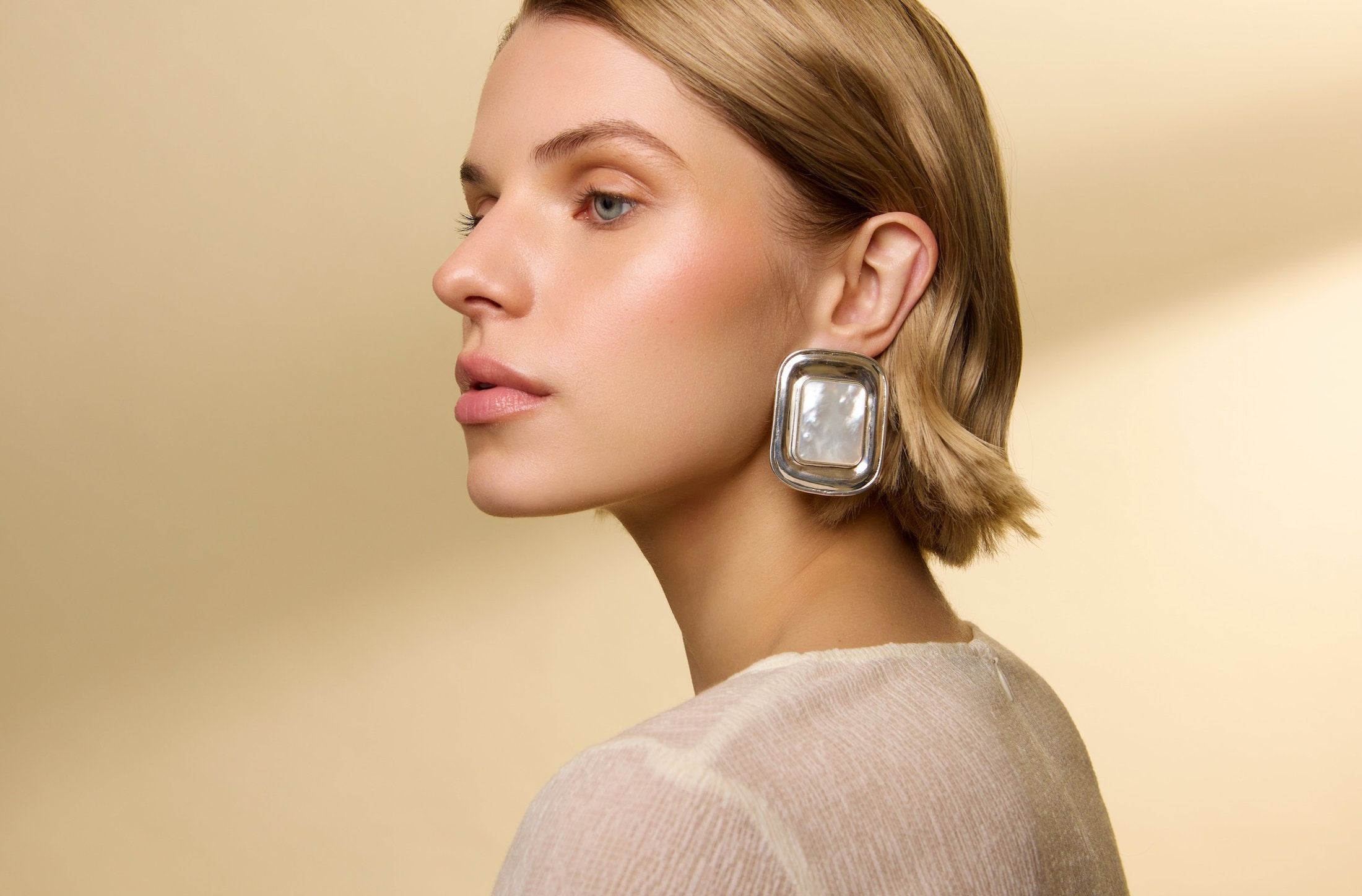 model image wearing oversized rectangle stud earrings in silver and mother of pearl 