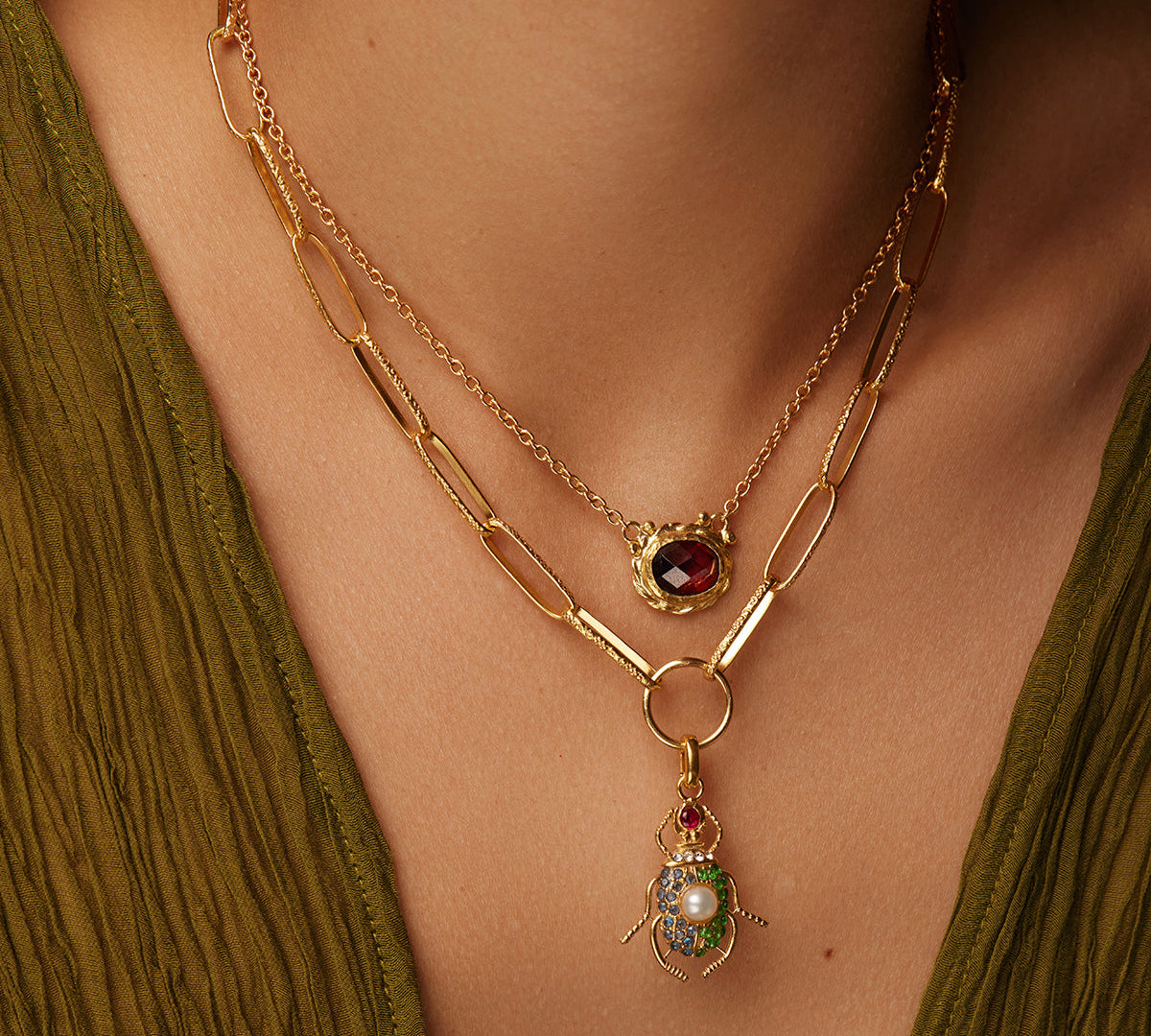 Image of Moels neck wearing a necklace with a beetle charm and a red stone necklace
