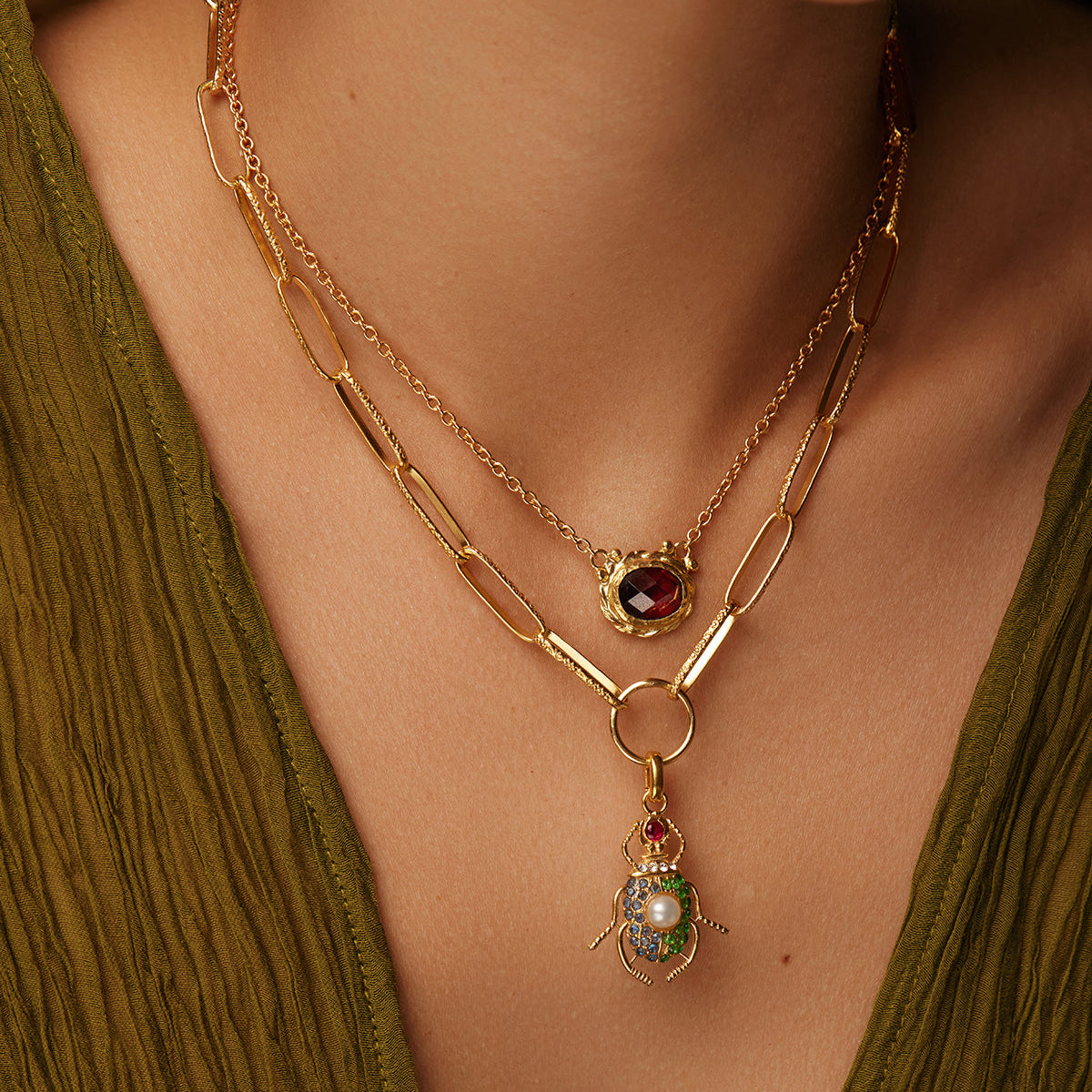 Image of Moels neck wearing a necklace with a beetle charm and a red stone necklace