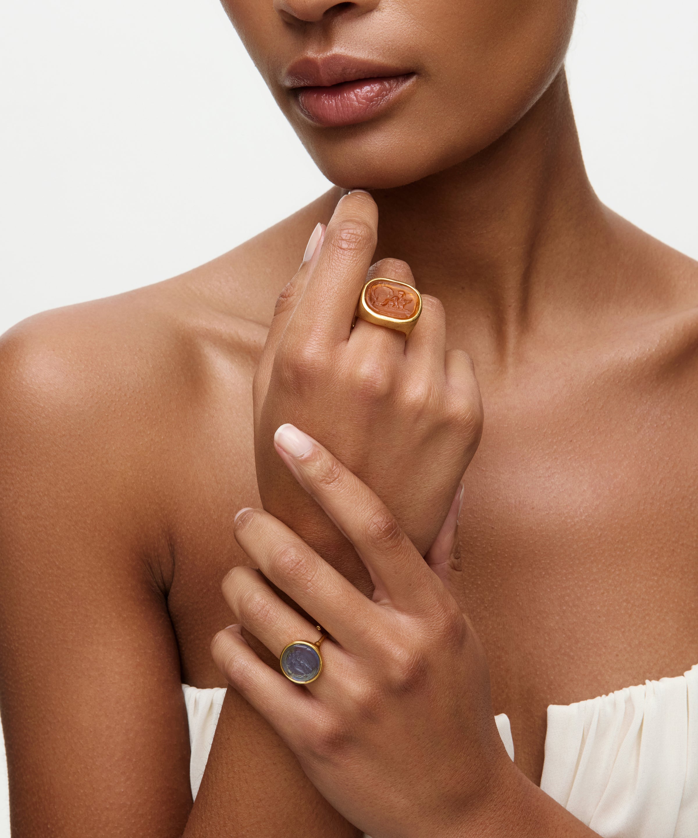 Woman wearing two rings on her fingers against a neutral background