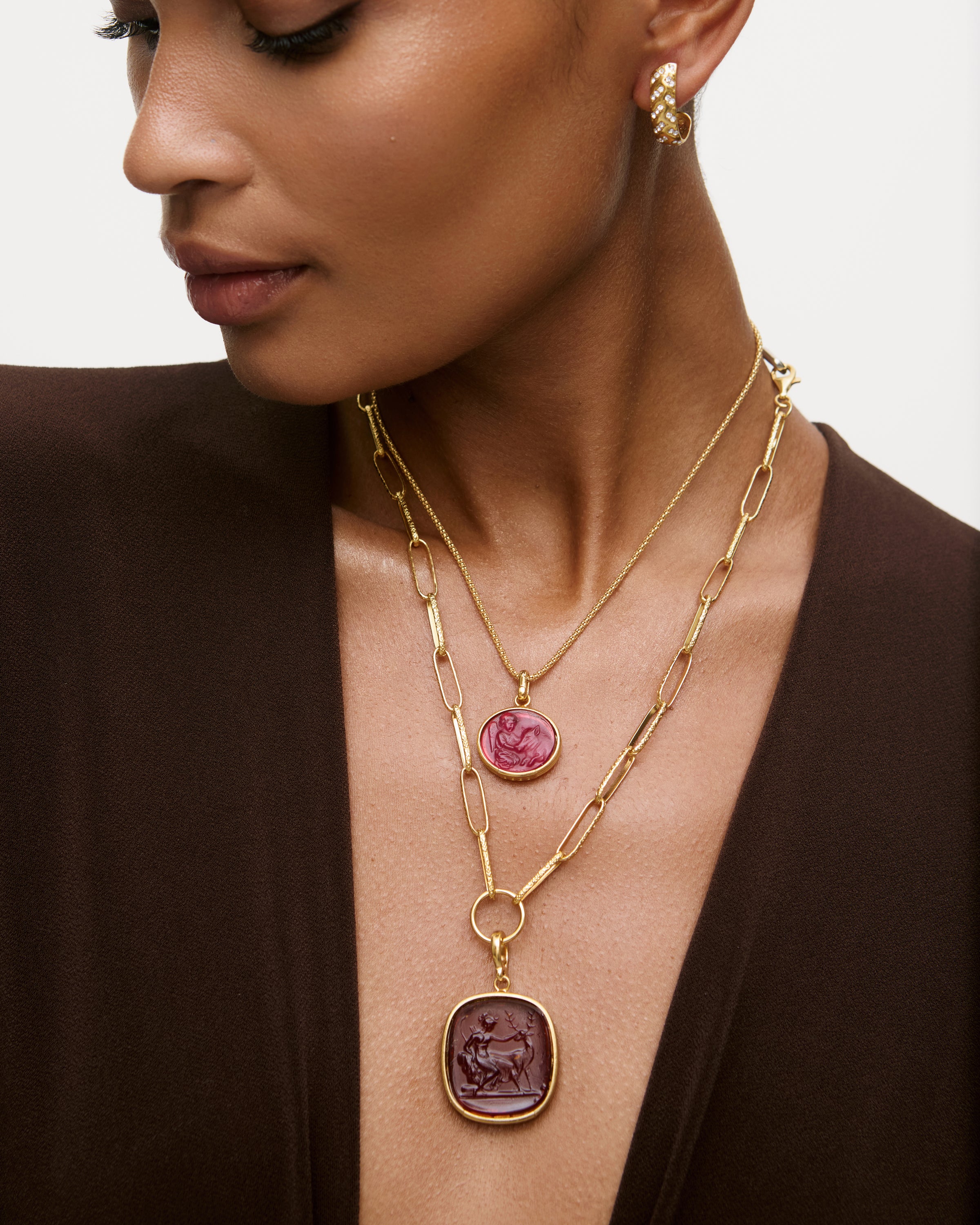 Close-up of a woman wearing a gold necklace with pink and purple pendants.
