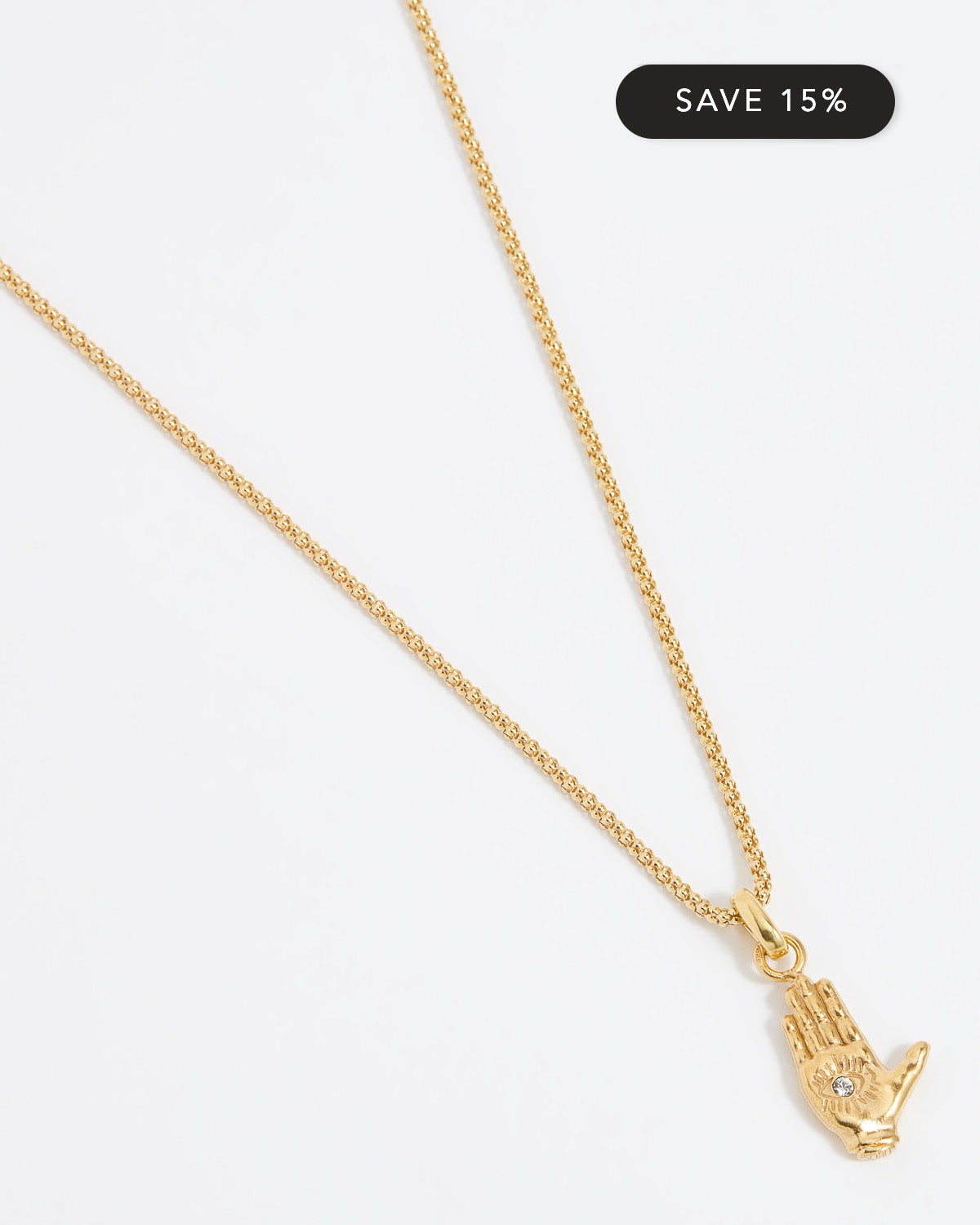 Close up shot of a gold hand-shaped charm featuring an inset eye symbol in the palm, set with a clear crystal hung from a Soru rope chain on a white background.