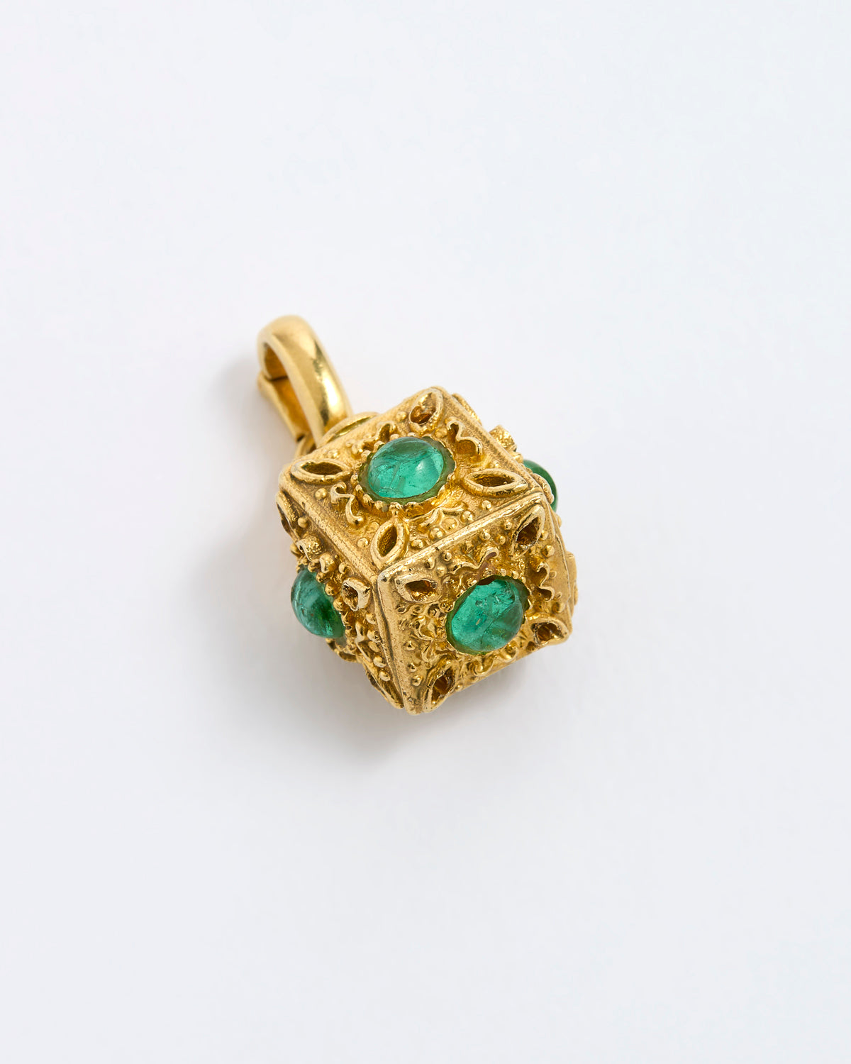 A gold cube charm featuring green emerald-cut gemstones on each side, on a white background.
