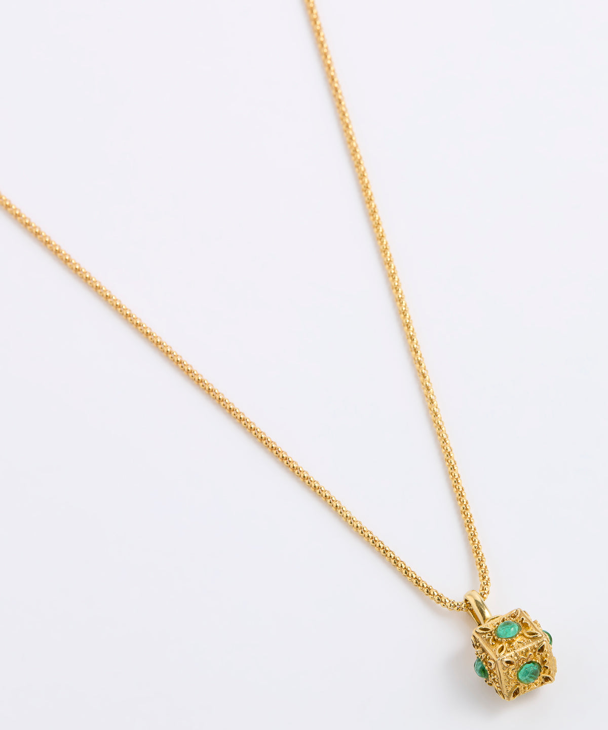 A gold chain necklace with a small cube pendant featuring green gemstone accents, displayed on a white background.
