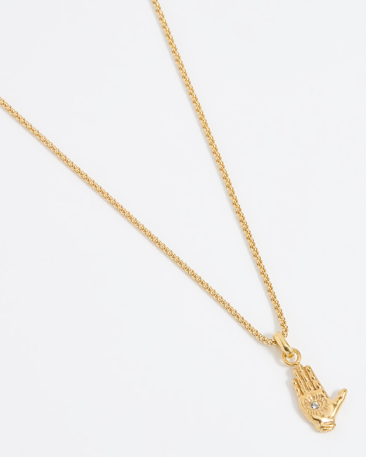 Close up shot of a gold hand-shaped charm featuring an inset eye symbol in the palm, set with a clear crystal hung from a Soru rope chain on a white background.