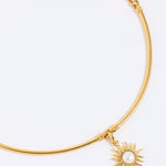 Gold choker with a sun-shaped charm on a white background