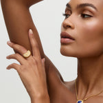 Woman wearing gold jewelry with a neutral background