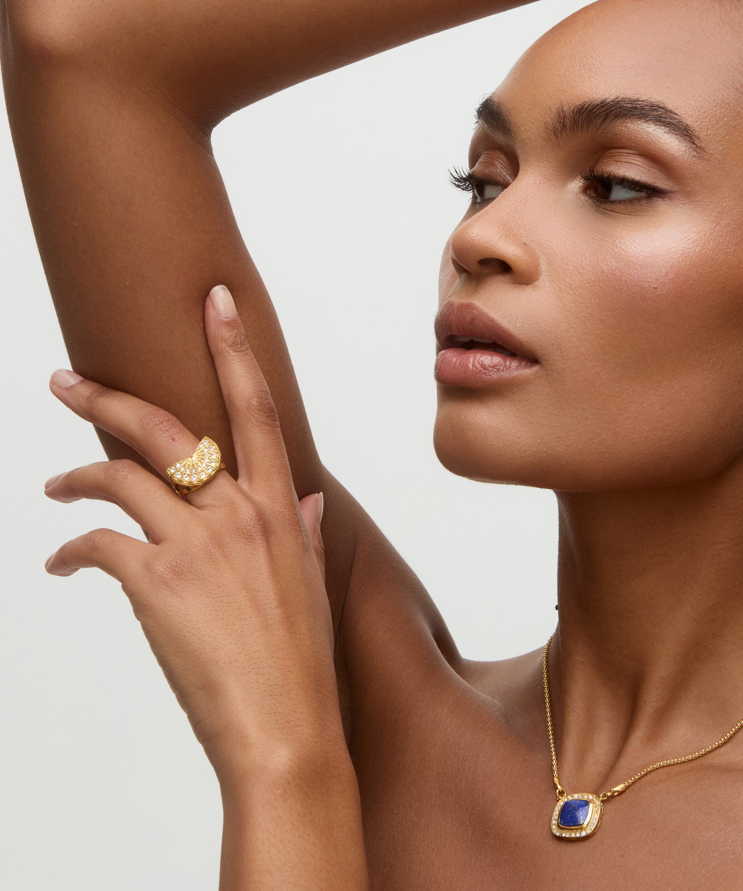 Woman wearing gold jewelry with a neutral background