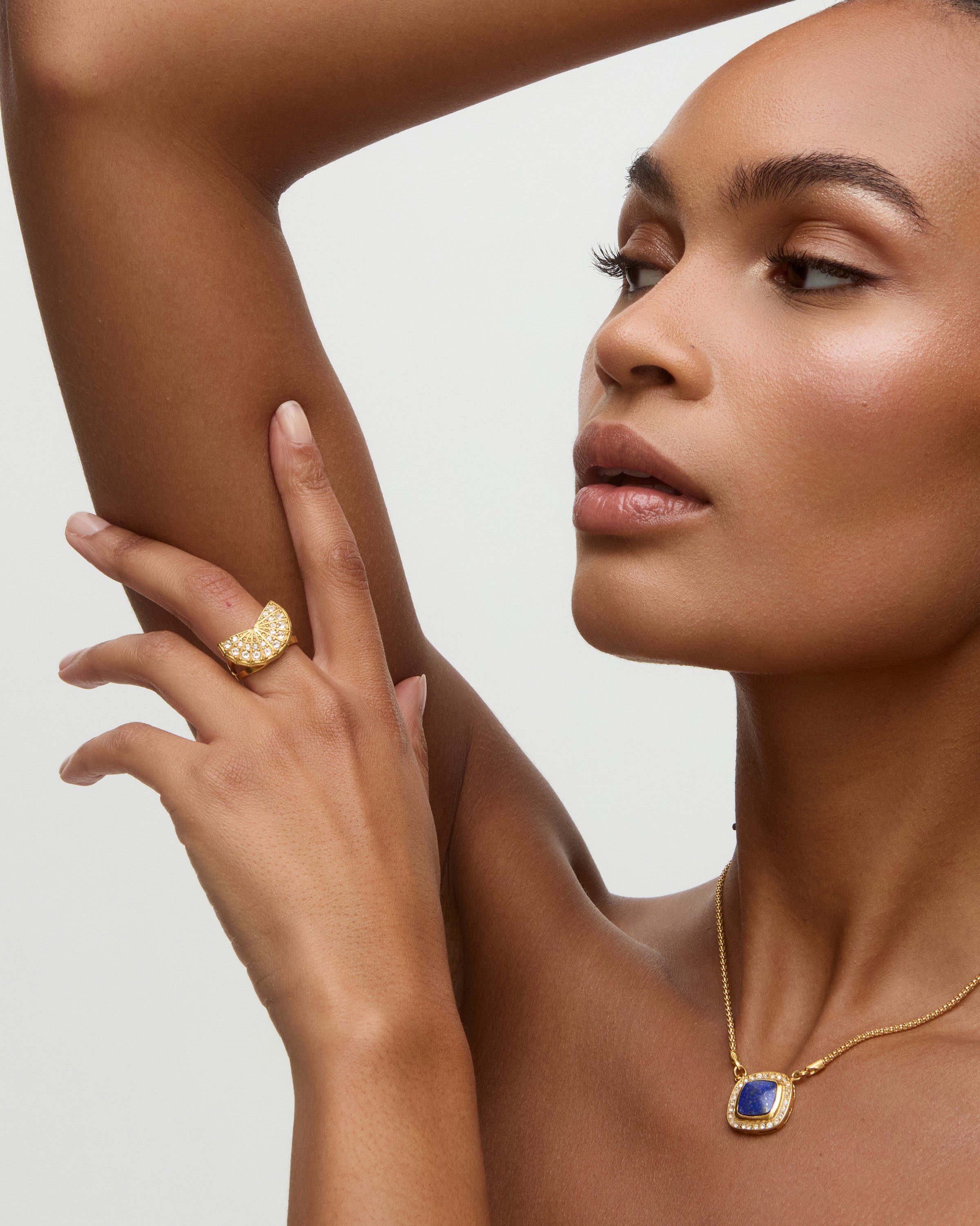 Woman wearing gold jewelry with a neutral background