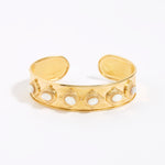 Gold cuff with intricate design and 6 small oval mother of pearls shown on a white background