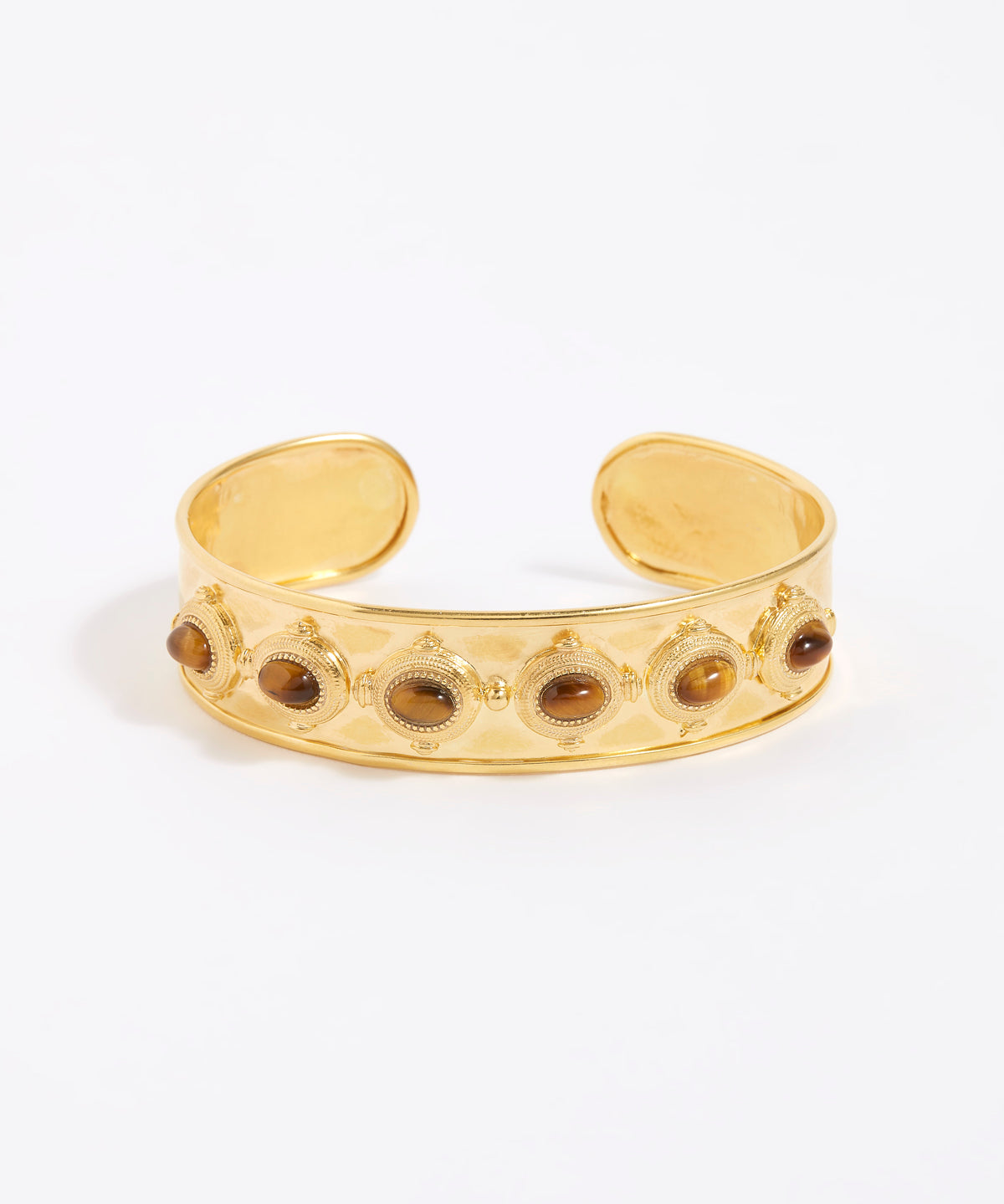 Gold cuff bracelet with embedded stones on a white background