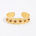 Gold cuff bracelet with embedded stones on a white background