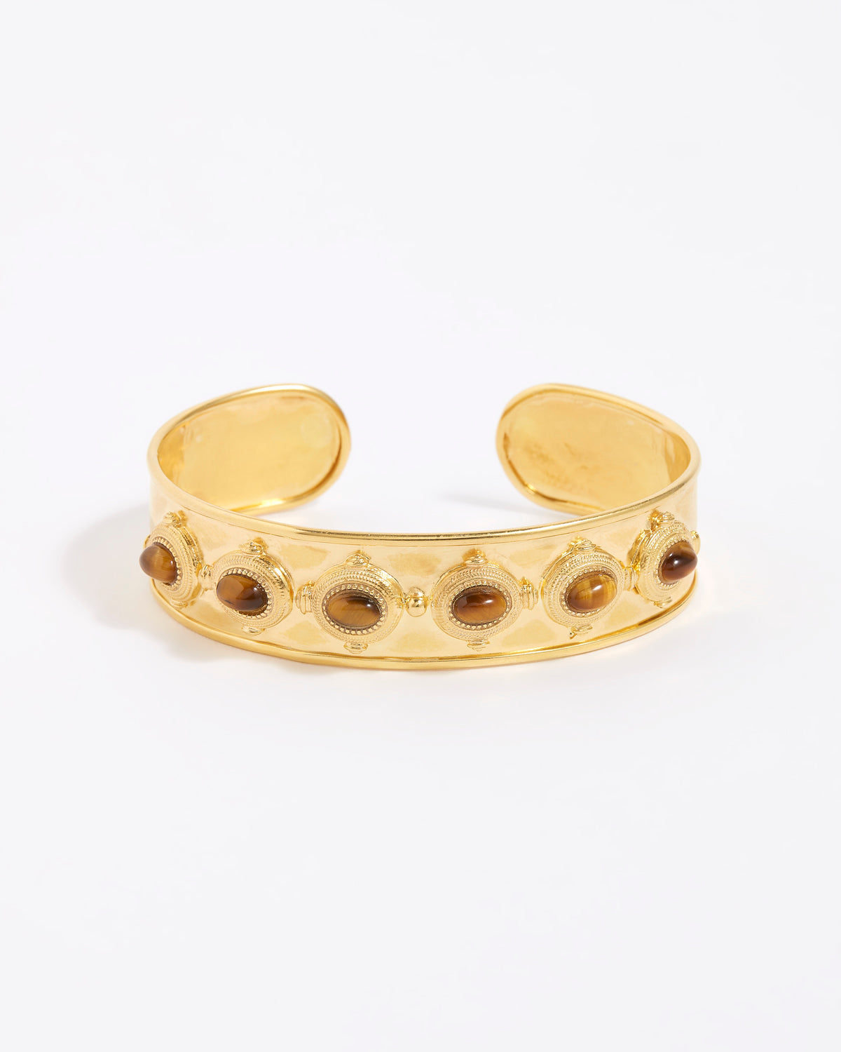 Gold cuff bracelet with embedded stones on a white background