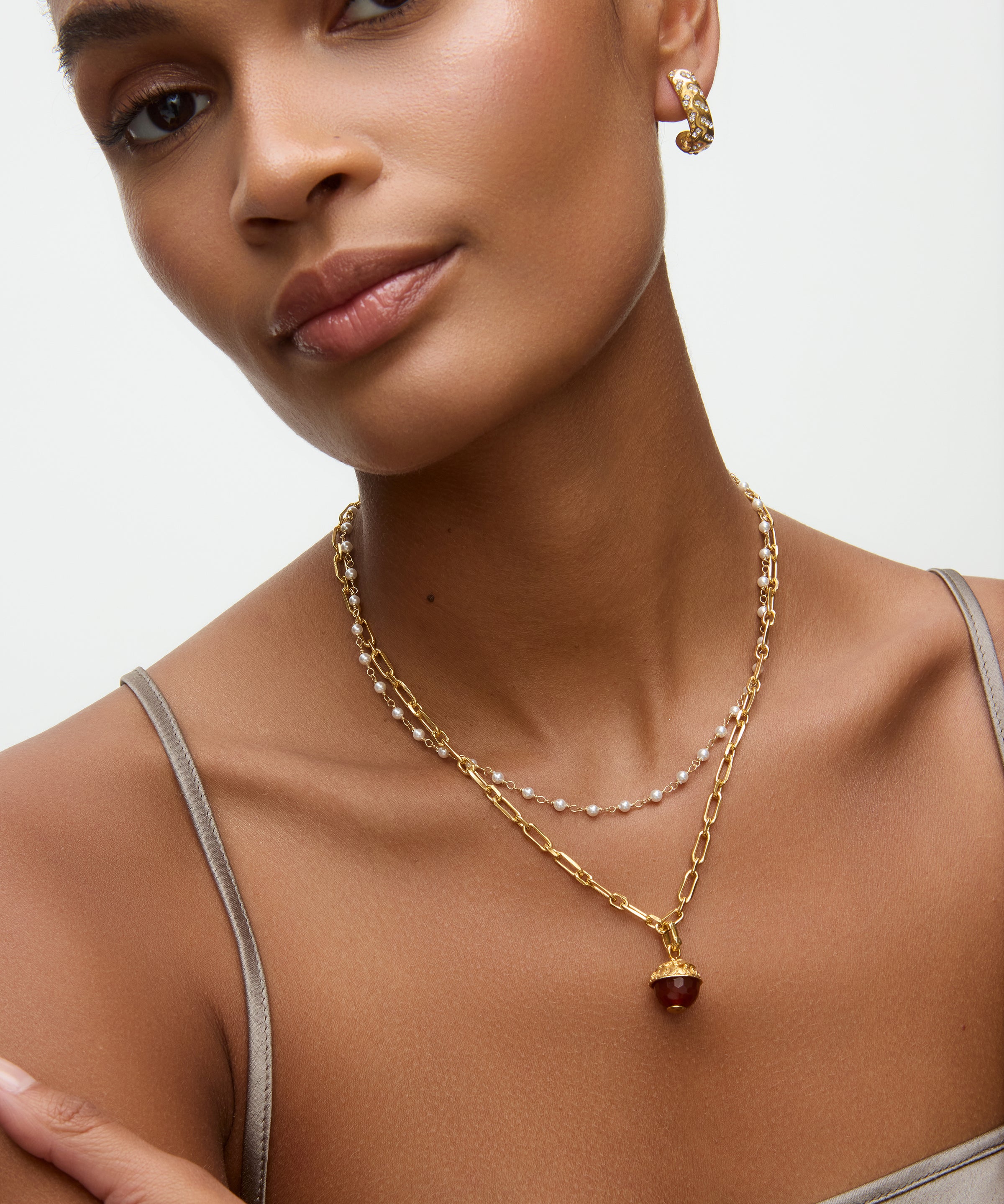 gold necklace with a brown glass pendant on a neutral background