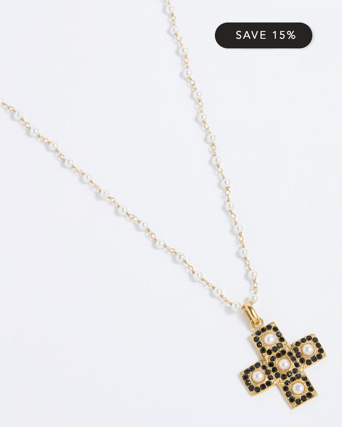 Gold necklace with a cross pendant on a white background, featuring a 'Save 15%' label.