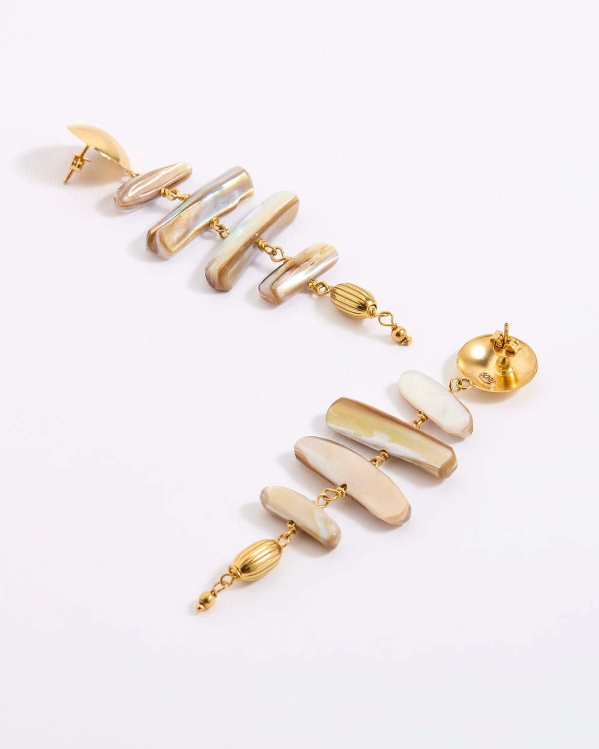 A pair of gold-tone drop earrings featuring irregular, polished shell-like segments in cream, beige, and white, accented with small gold beads, shown on a clean white background.