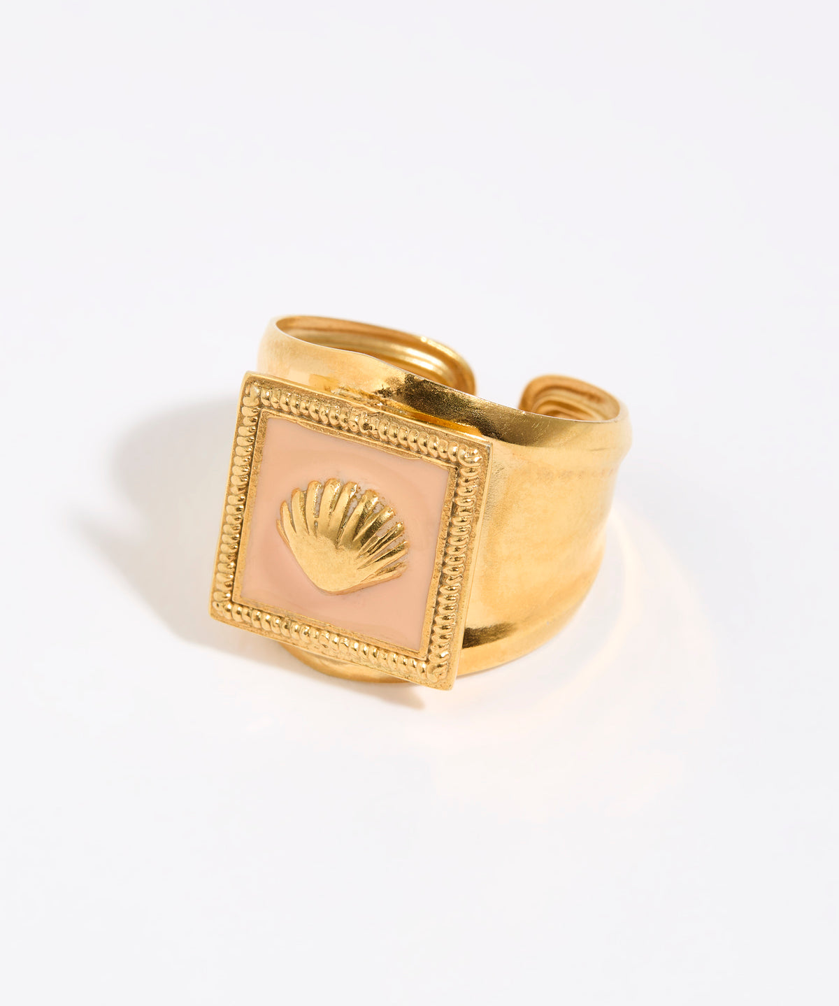 Gold ring with a shell design within peach coloured enamel square setting,  on a light background
