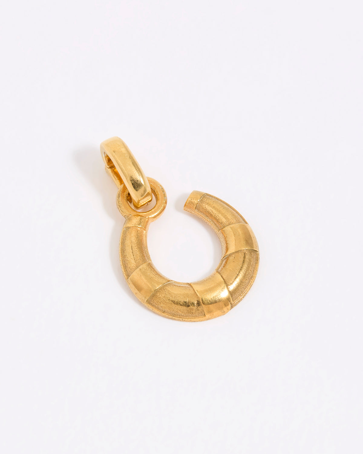 Small gold coloured horse shoe charm on white background