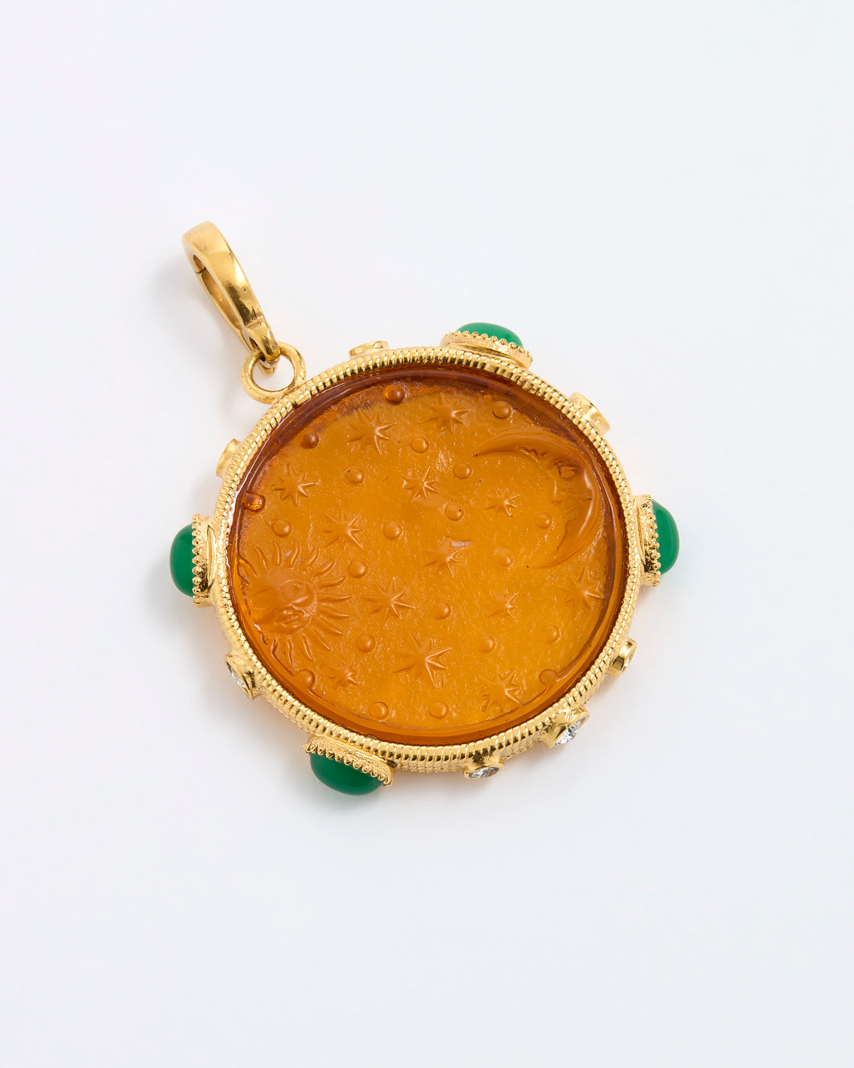 A round gold pendant featuring an amber-colored carved center with green stone accents at the corners, shown on a plain white background.