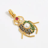 product shot of scarab beetle charm encrusted with red, bue and green crystals and one pearl on the back