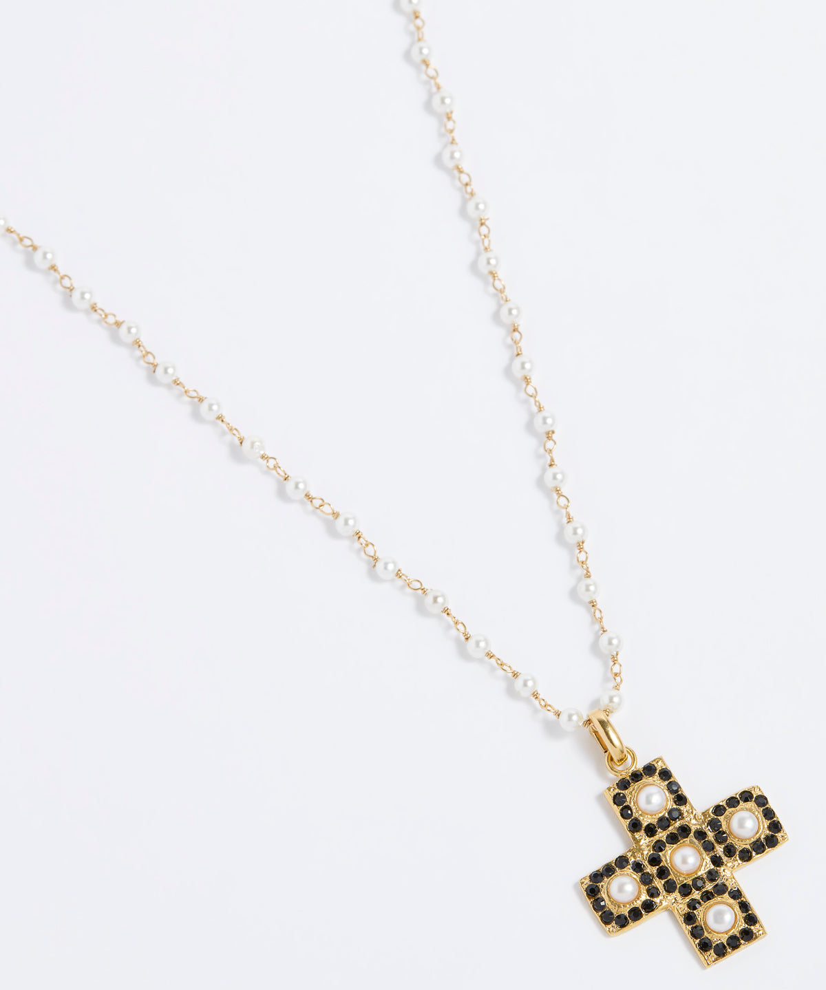 Product image of a gold textured cross-shaped pendant embellished with alternating baroque pearls and black crystals hung from a Soru pearl charm chain on a white background.