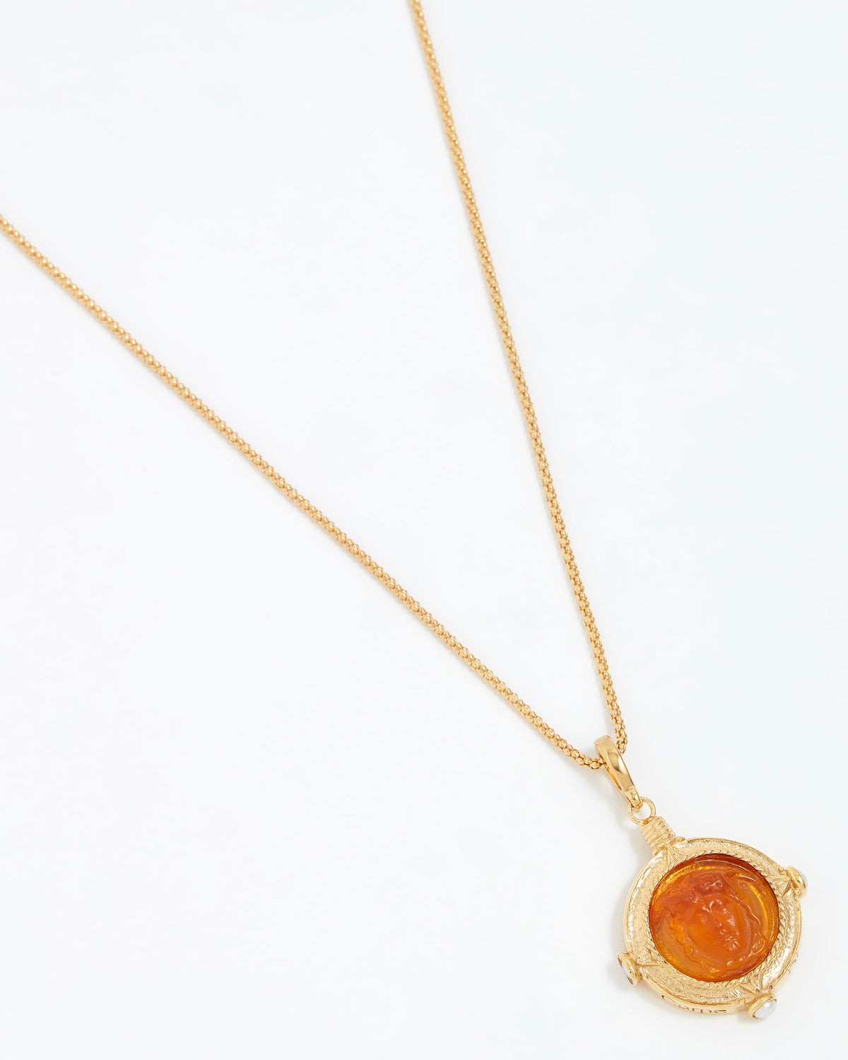 Gold necklace with a circular pendant on a white background