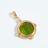 Gold pendant with green gemstone on a white background