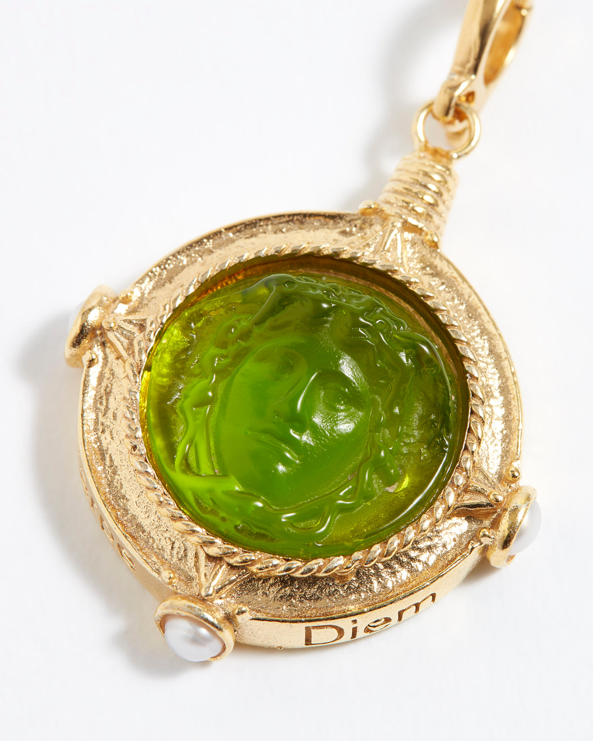 Gold pendant with green stone on a white background