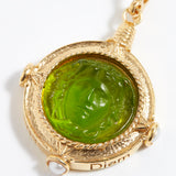 Gold pendant with green stone on a white background