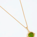 Gold necklace with a green pendant on a white background