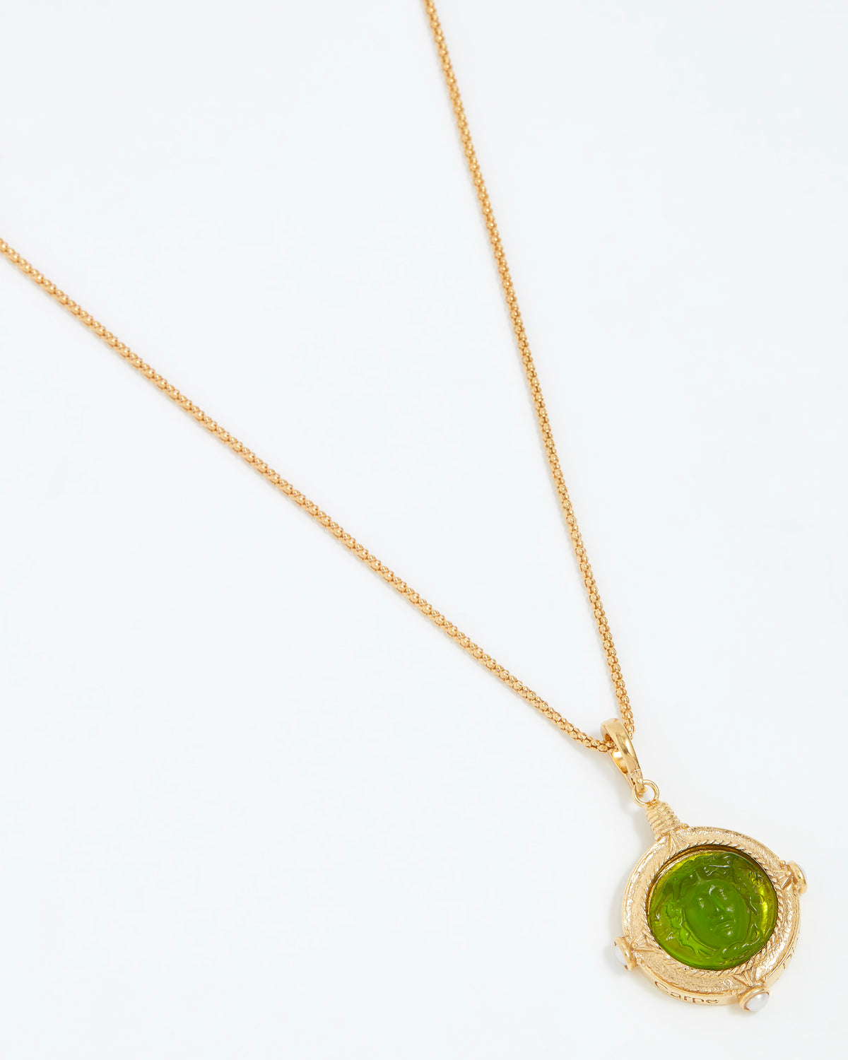 Gold necklace with a green pendant on a white background