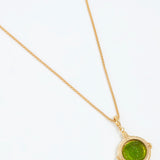 Gold necklace with a green pendant on a white background