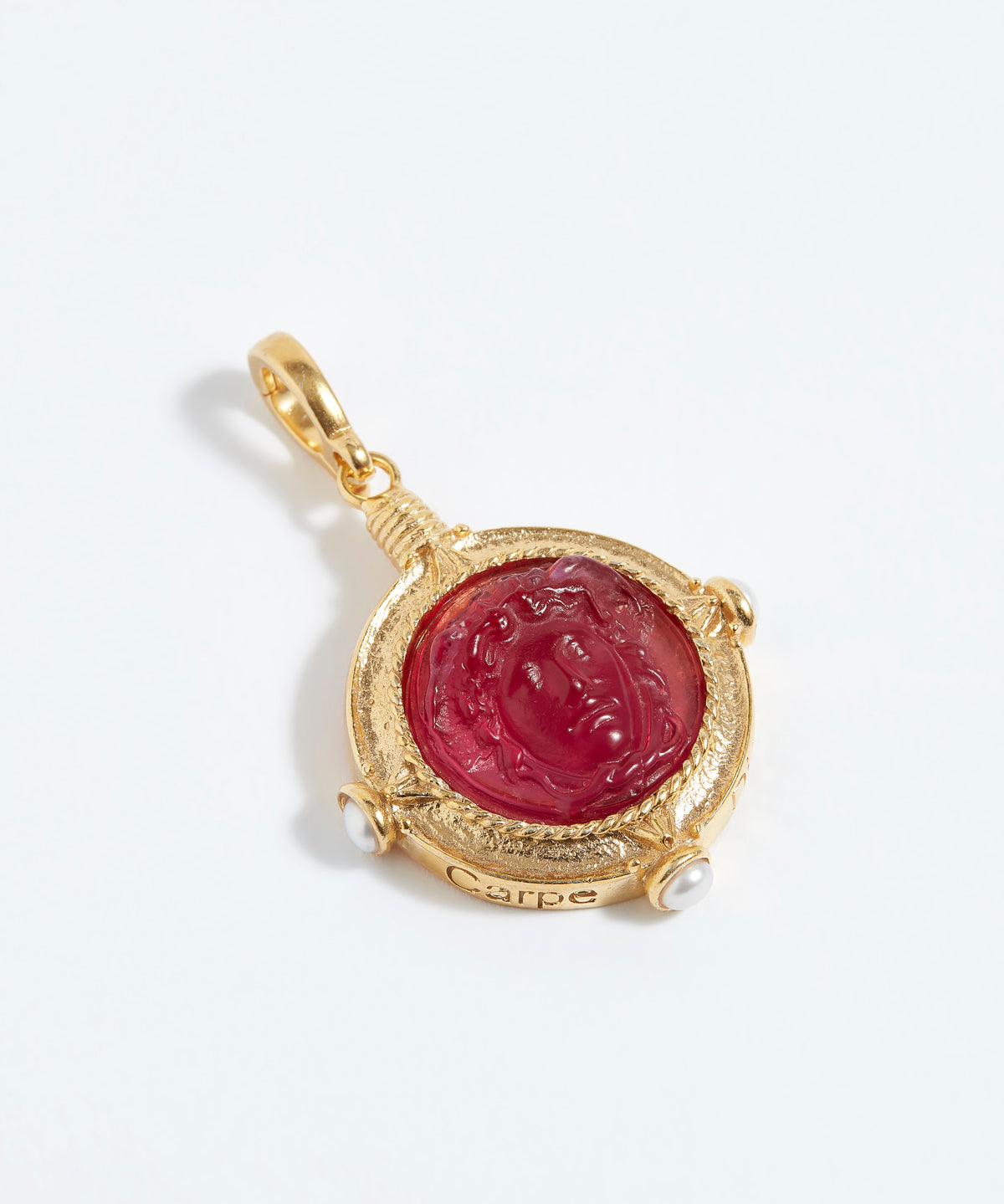 Gold pendant with a red stone on a white background