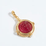 Gold pendant with a red stone on a white background