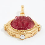 Gold pendant with red stone and pearl on a white background