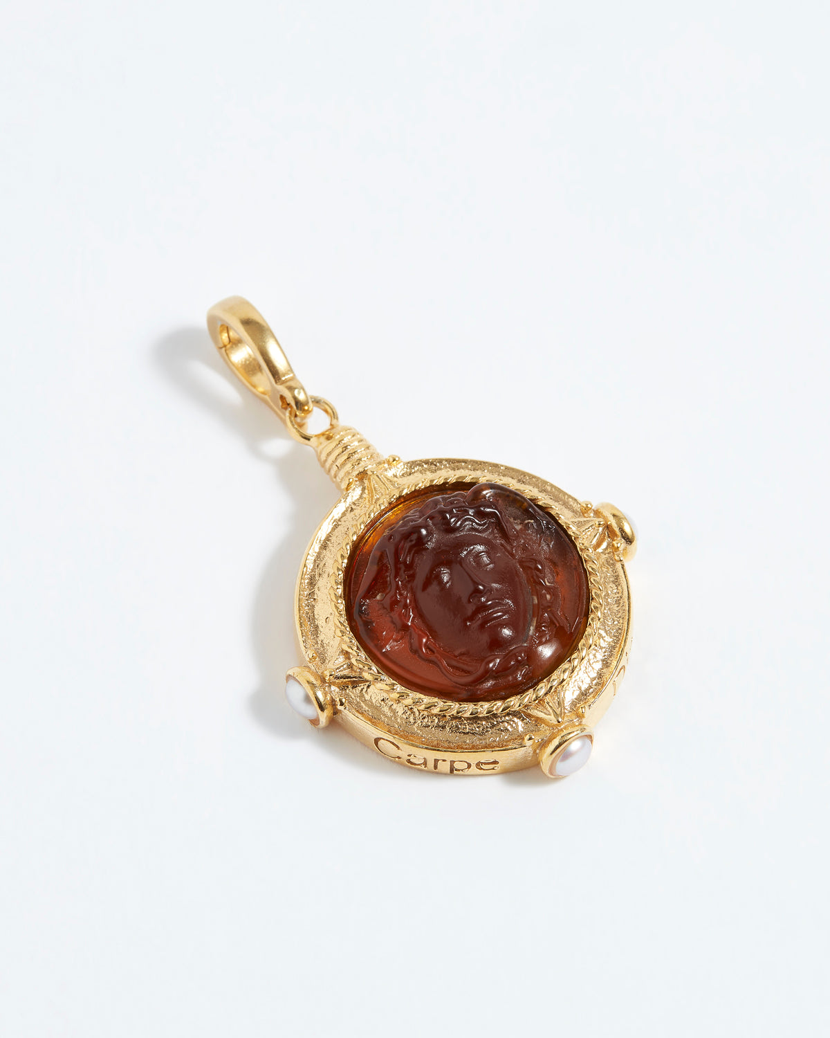 Gold pendant with a face design on a white background
