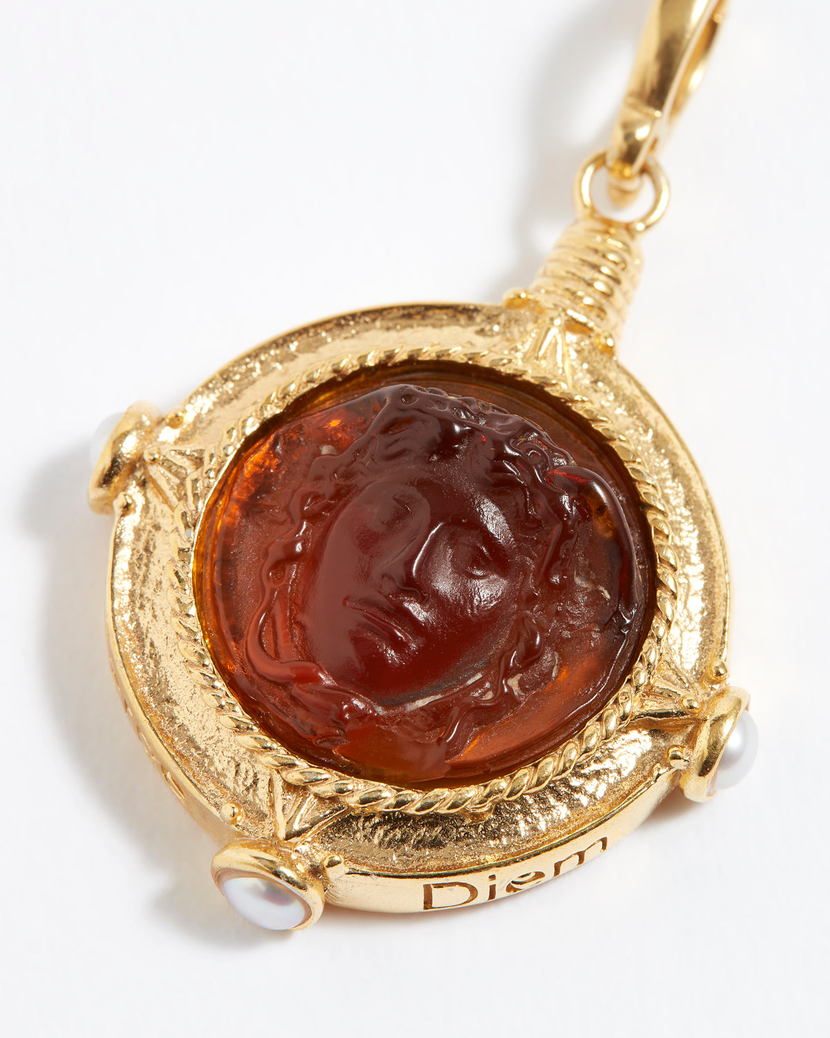 Gold pendant with a face design on a white background