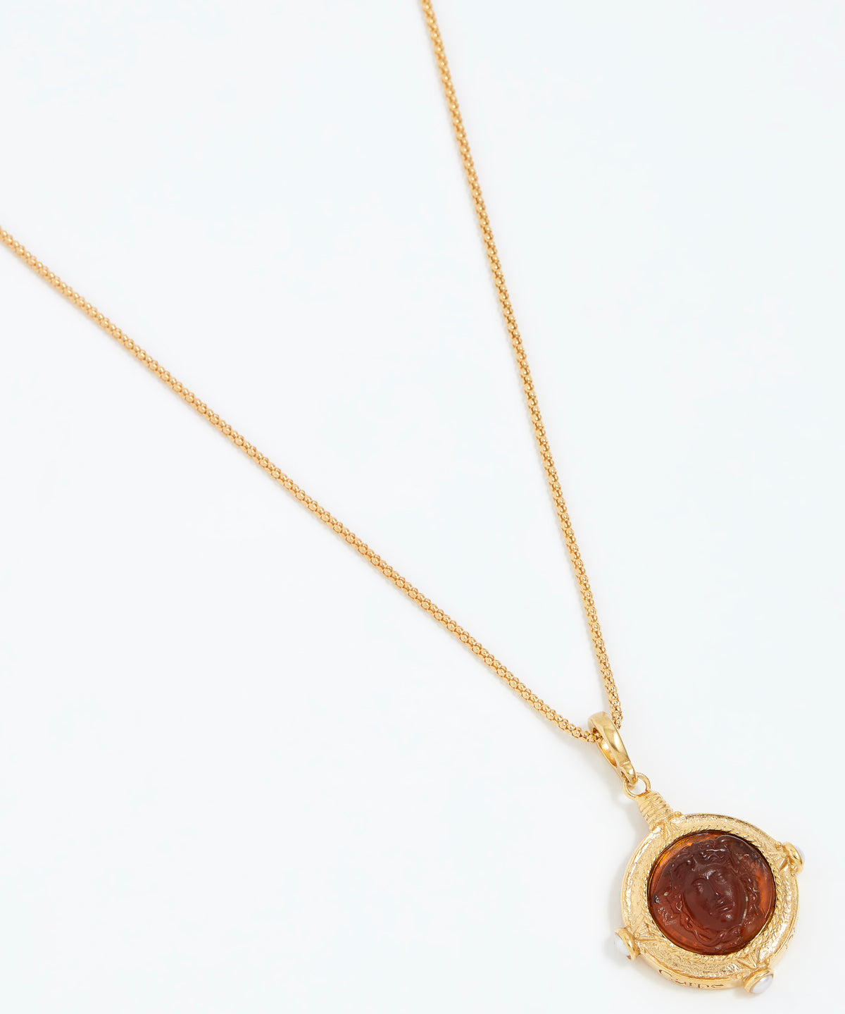 Gold necklace with a circular pendant on a white background