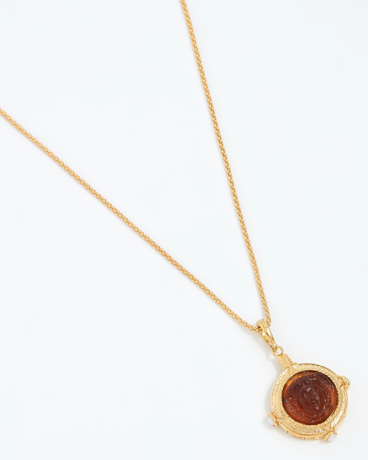 Gold necklace with a circular pendant on a white background