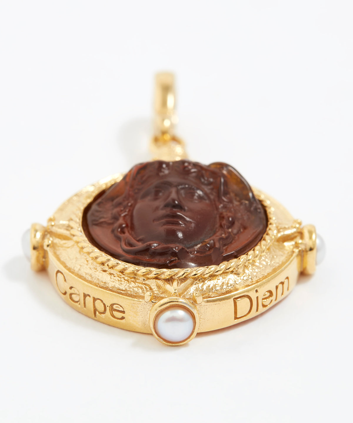 Gold pendant with a face design and 'Carpe Diem' engraving on a white background