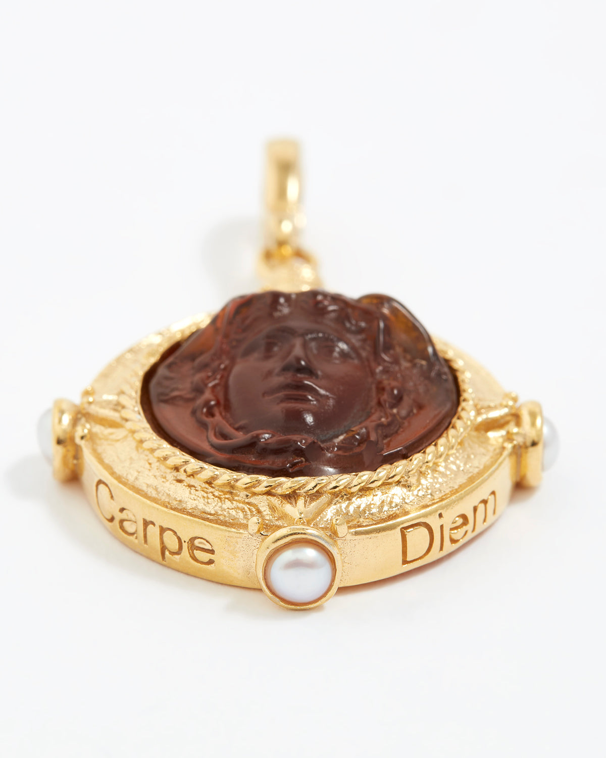 Gold pendant with a face design and 'Carpe Diem' engraving on a white background