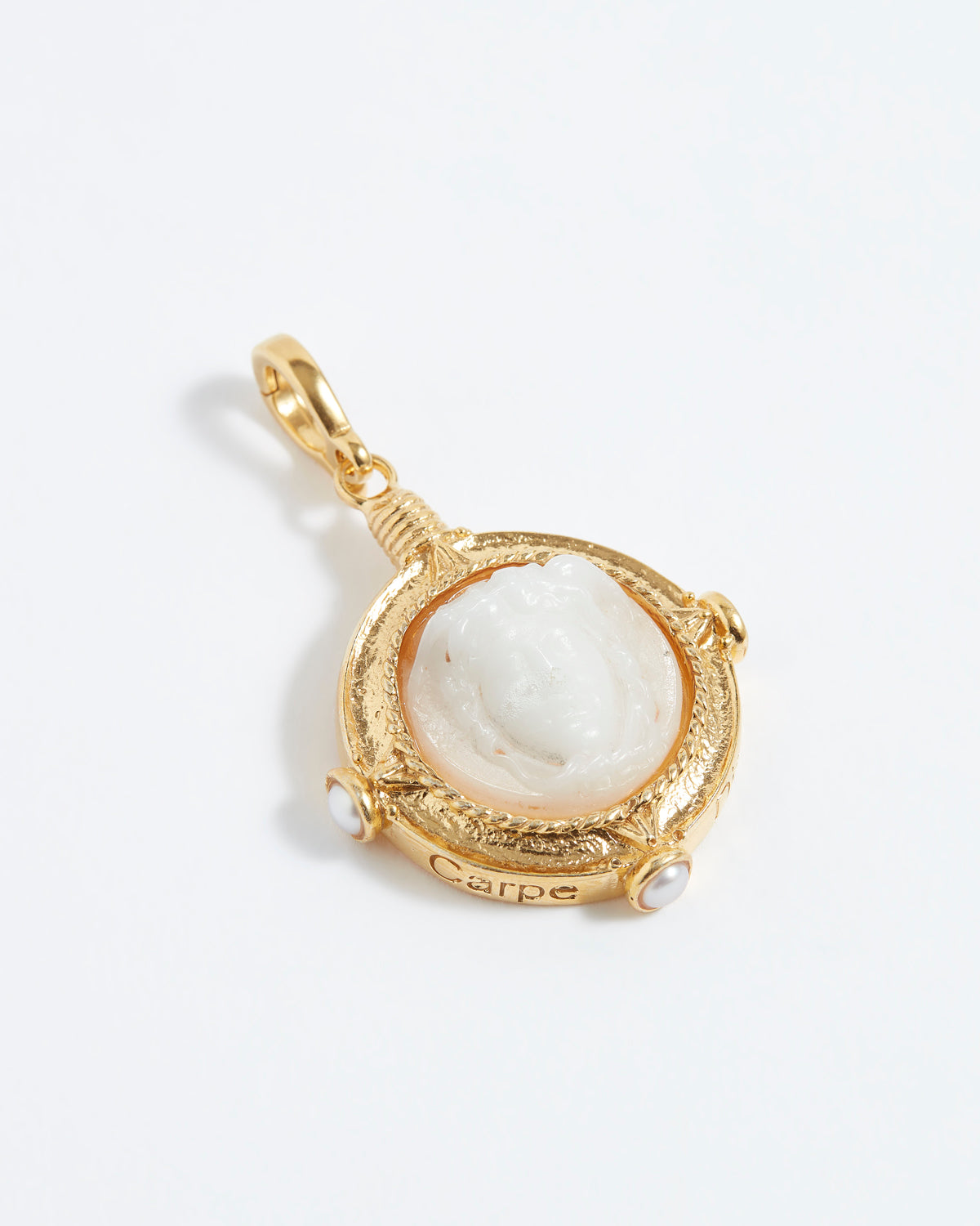 Gold pendant with a white stone on a light gray background
