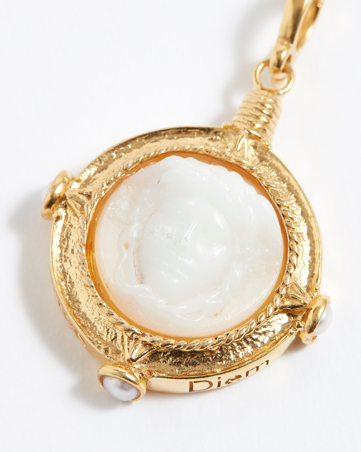 Gold pendant with a white stone engraved with wording  "Carpe Diem"  on a white background