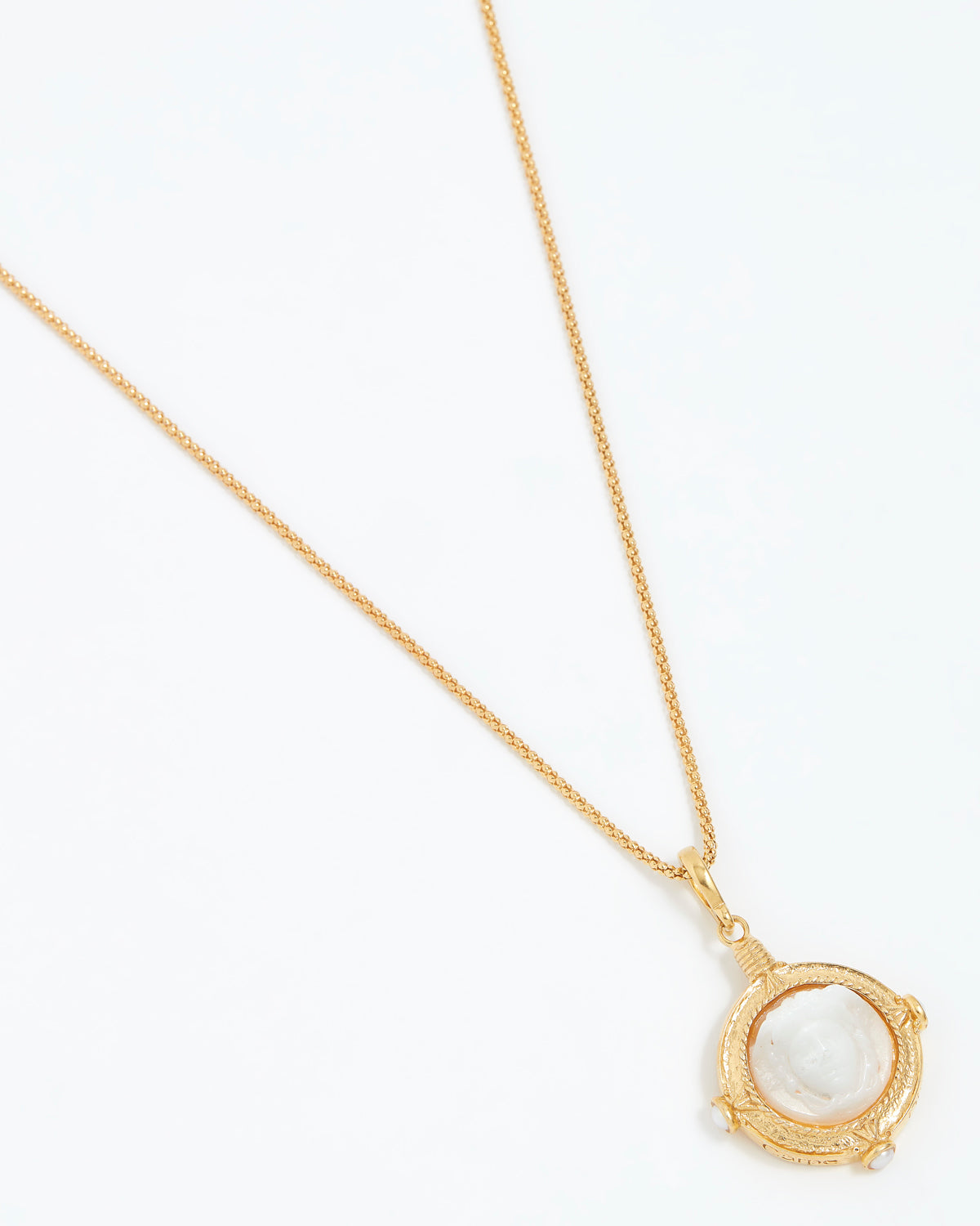 Gold necklace with a white pendant on a white background