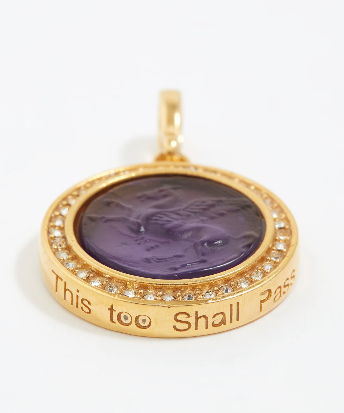 Gold pendant with purple stone and engraved text "this too shall pass" on a white background