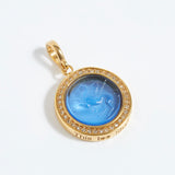 Gold pendant with blue stone and engraved text "this too shall pass" on a white background